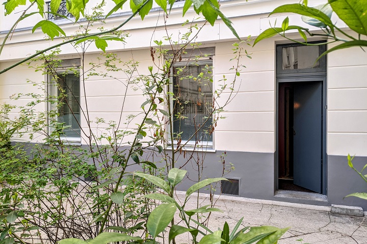 Cour d'immeuble végétalisée et porte d'entrée du studio